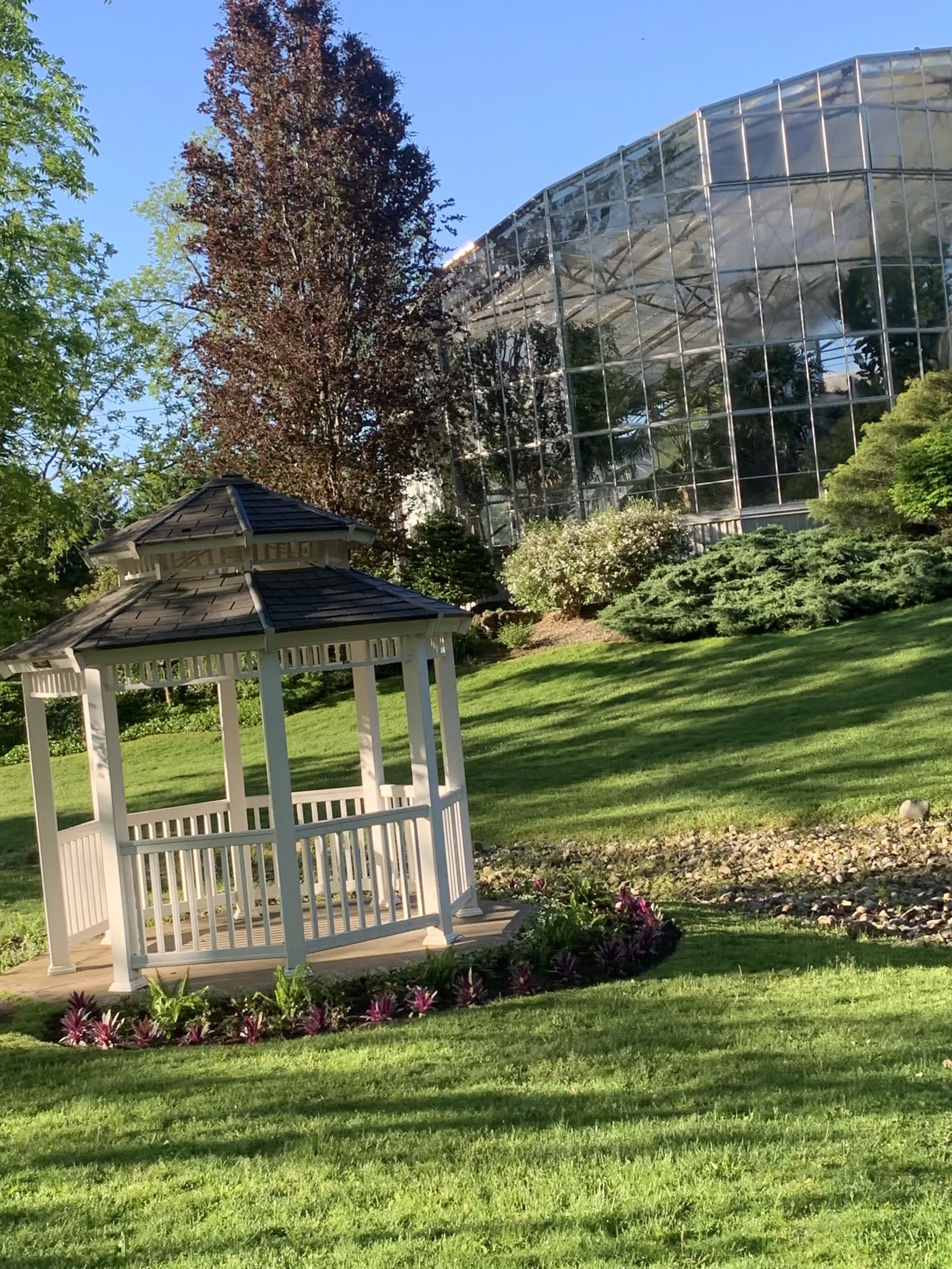 A white gazebo on the gardens beside the glass conservatory